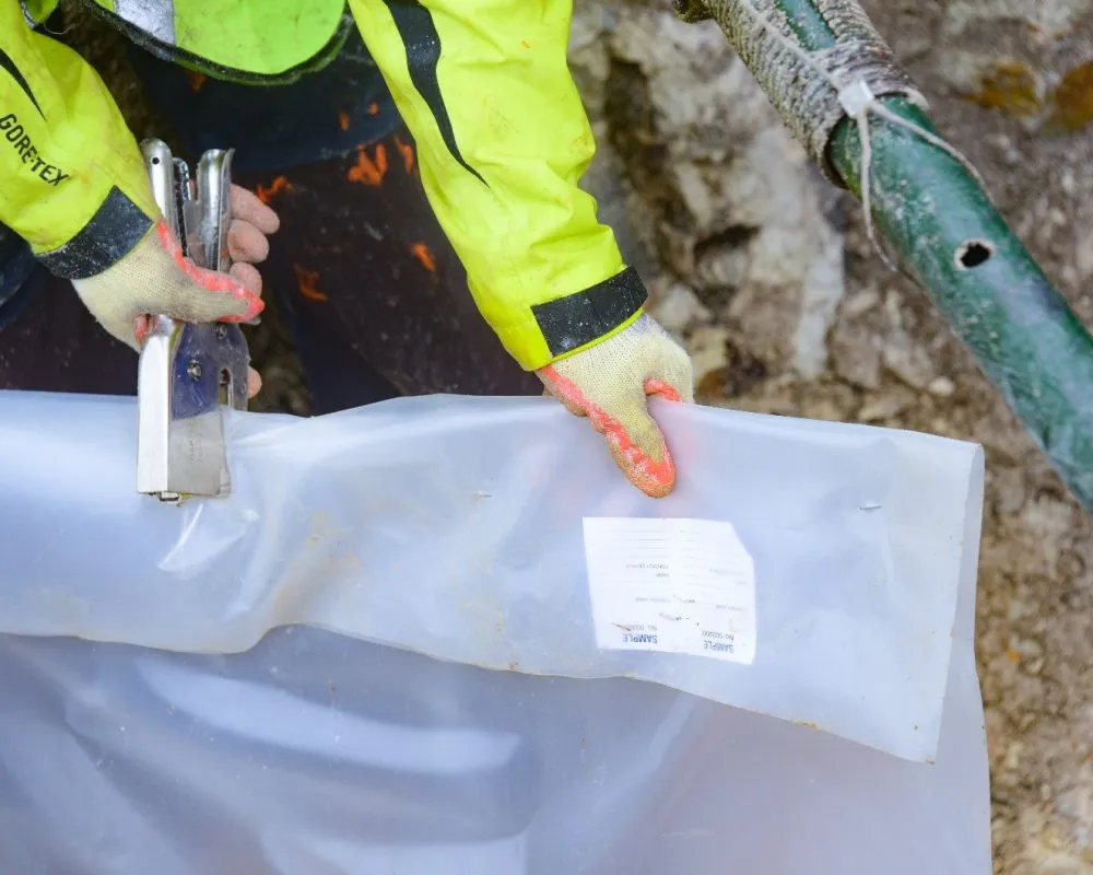 Geological sampling bag labeled with ID tickets being sealed at British Lithium exploration site for traceability and analysis.