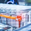 Close-up of electric vehicle lithium-ion battery pack with orange high-voltage cable, highlighting clean energy storage technology.