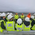 Students and workers in safety helmets and high-visibility jackets with Imerys logo during an educational quarry site visit
